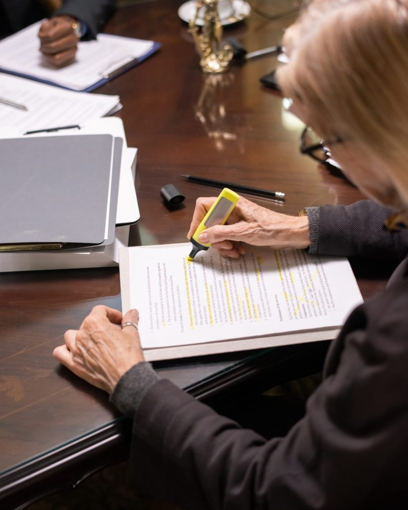 Contemporary businesswoman or lawyer highlighting terms and conditions of new contract Contemporary mature businesswoman or lawyer highlighting terms and conditions of new contract by workplace